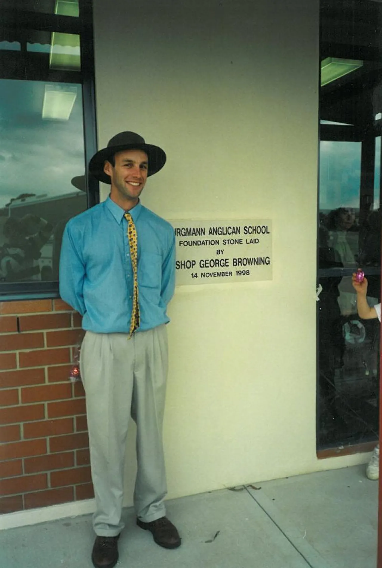 Dr Paul Browning OAM standing next to Burgmann Anglican School's Foundation Stone.