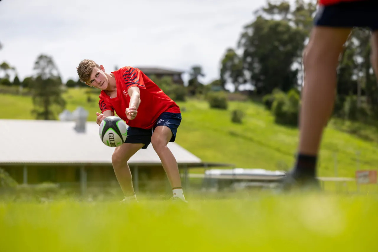 A young elite athlete executing a pass on the field, representing flexible online schooling for athletes.