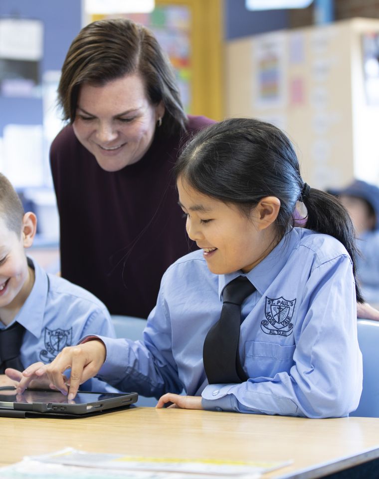 Primary school students using iPad with teacher.