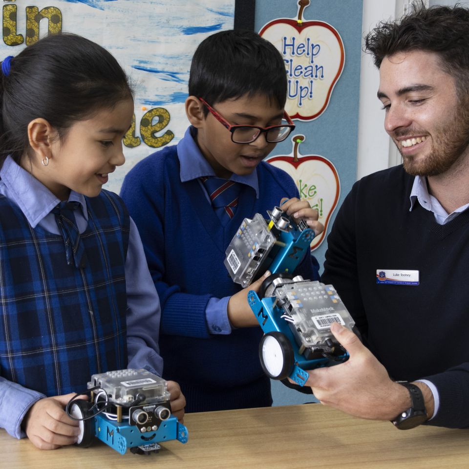 Primary school students using robots with teacher.