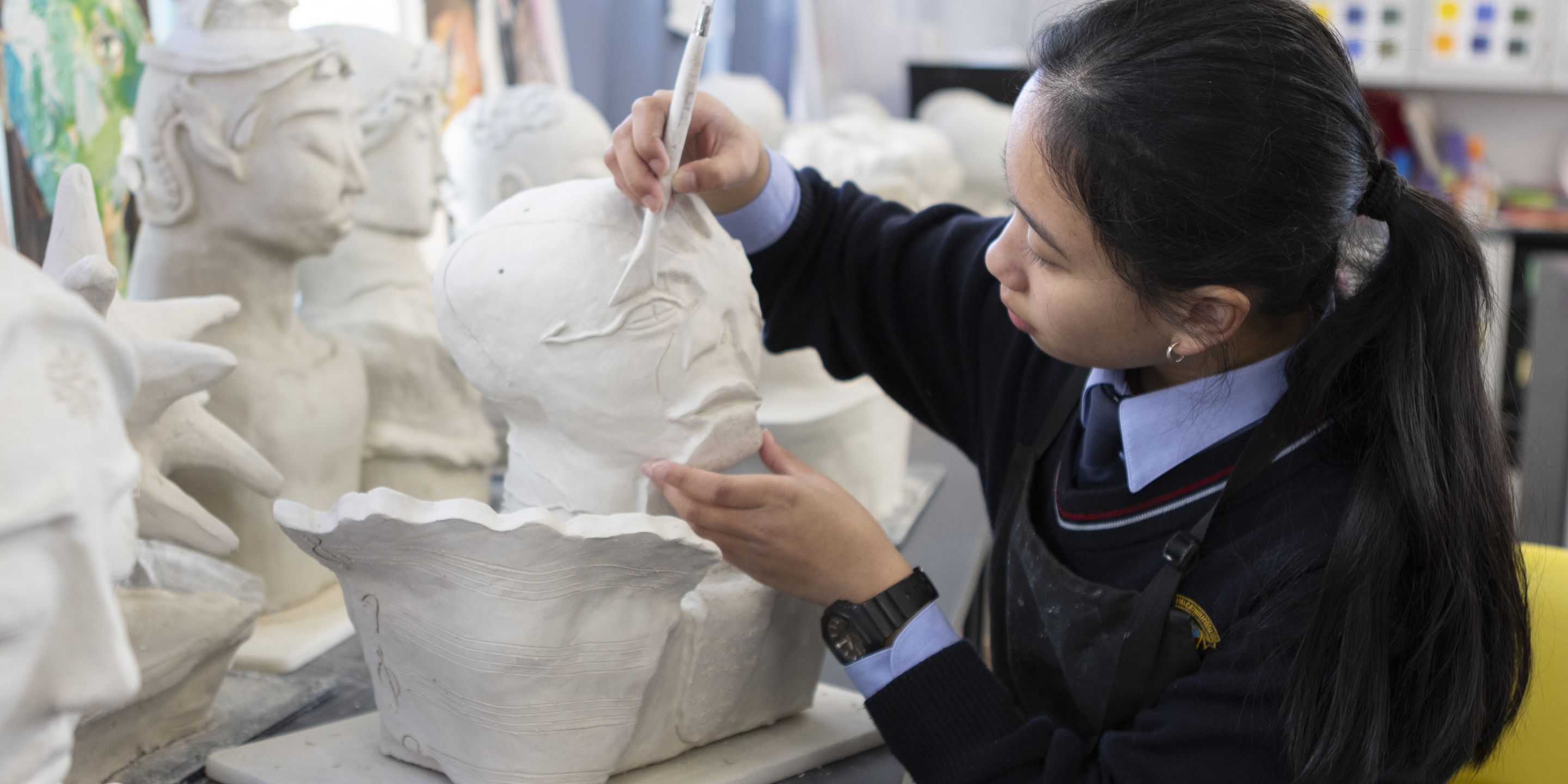 High school student creating clay sculpture.