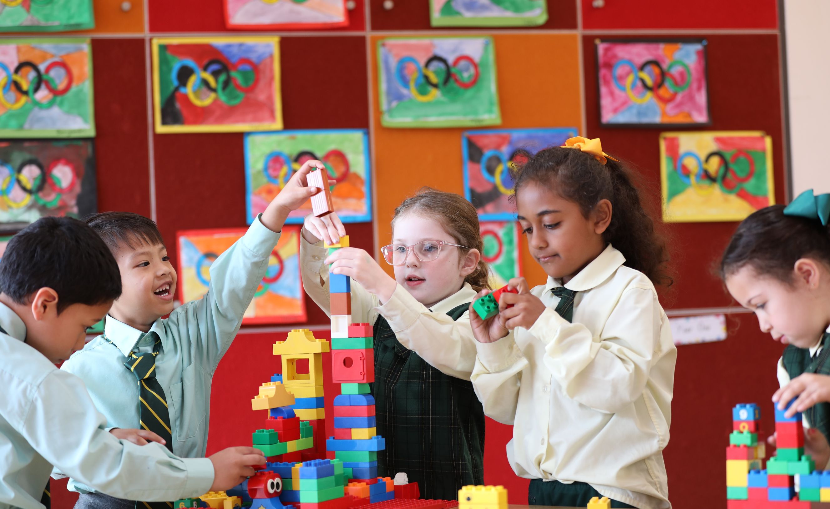 Primary school students playing with building blocks at desk.