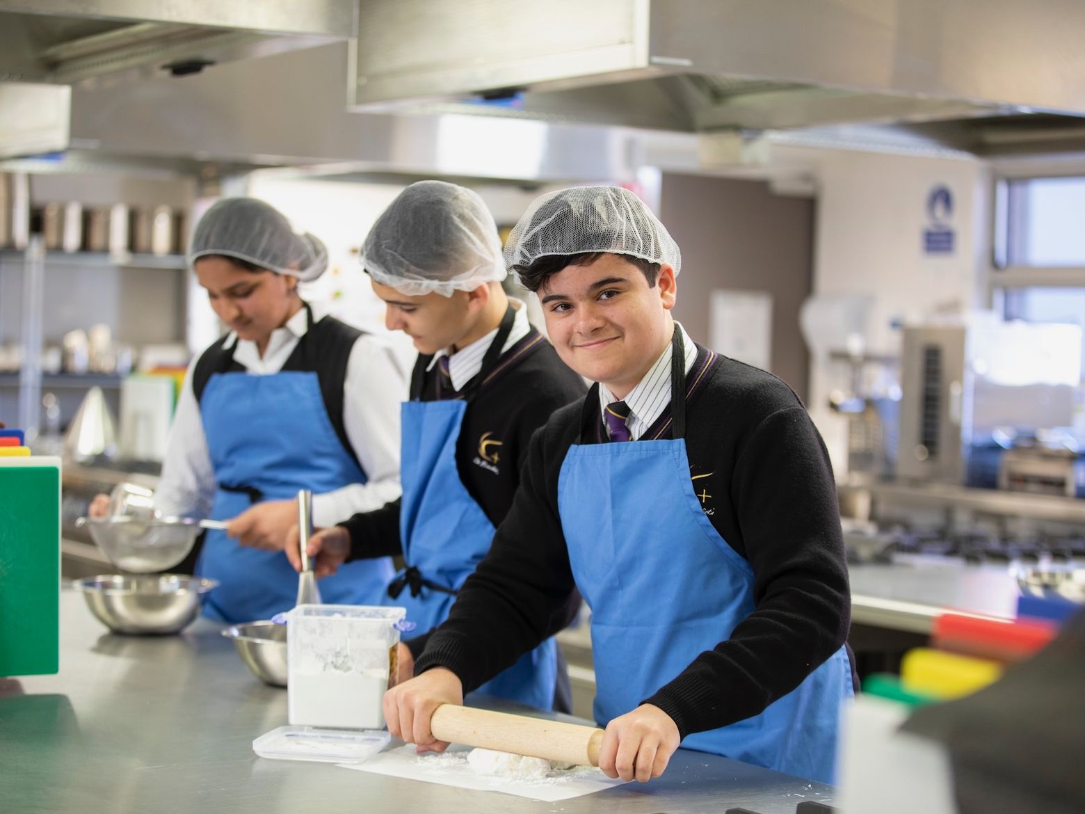 High school student rolling dough with rolling pin.