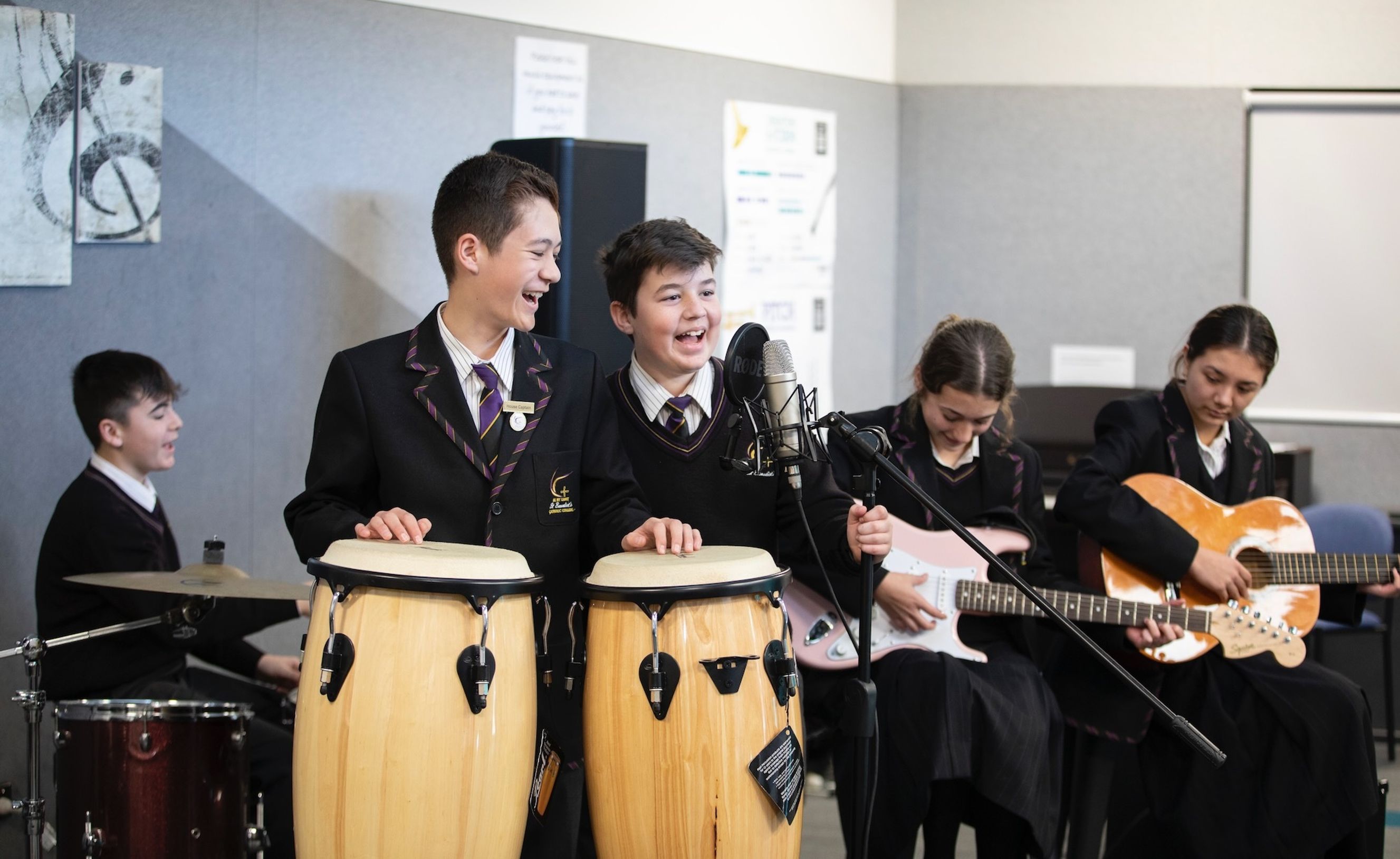 High school students playing drums and guitar while singing.