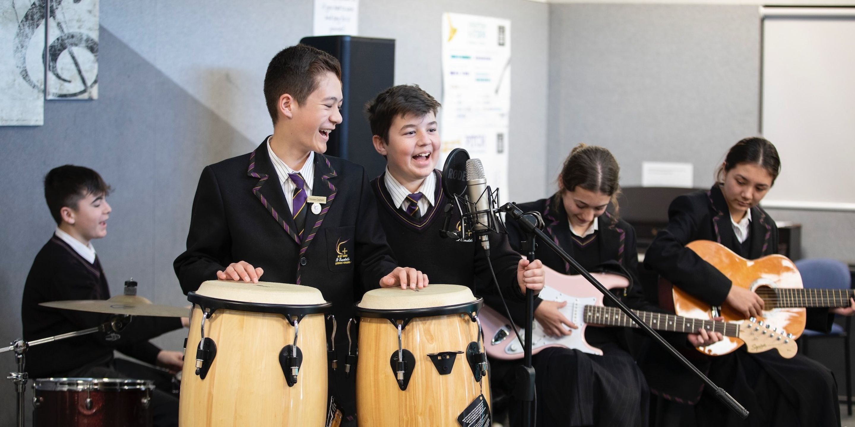 High school students playing drums and guitar while singing.