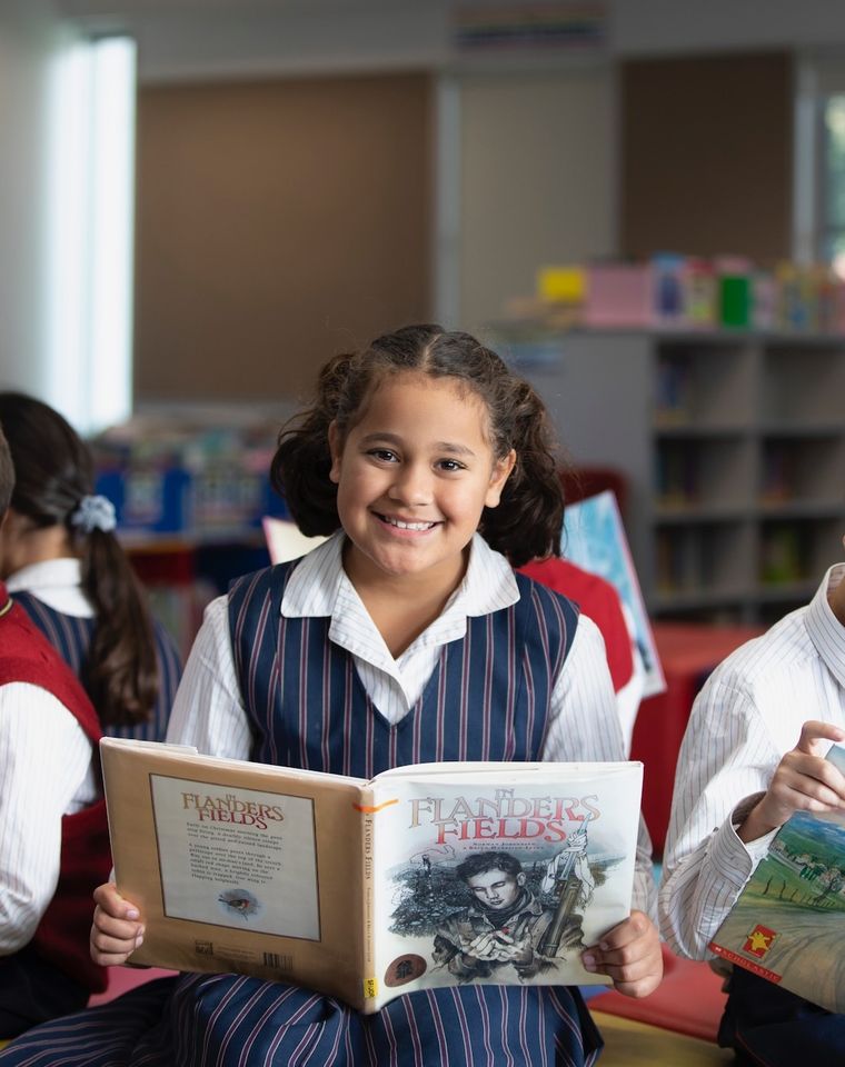 Primary school students reading books in library.