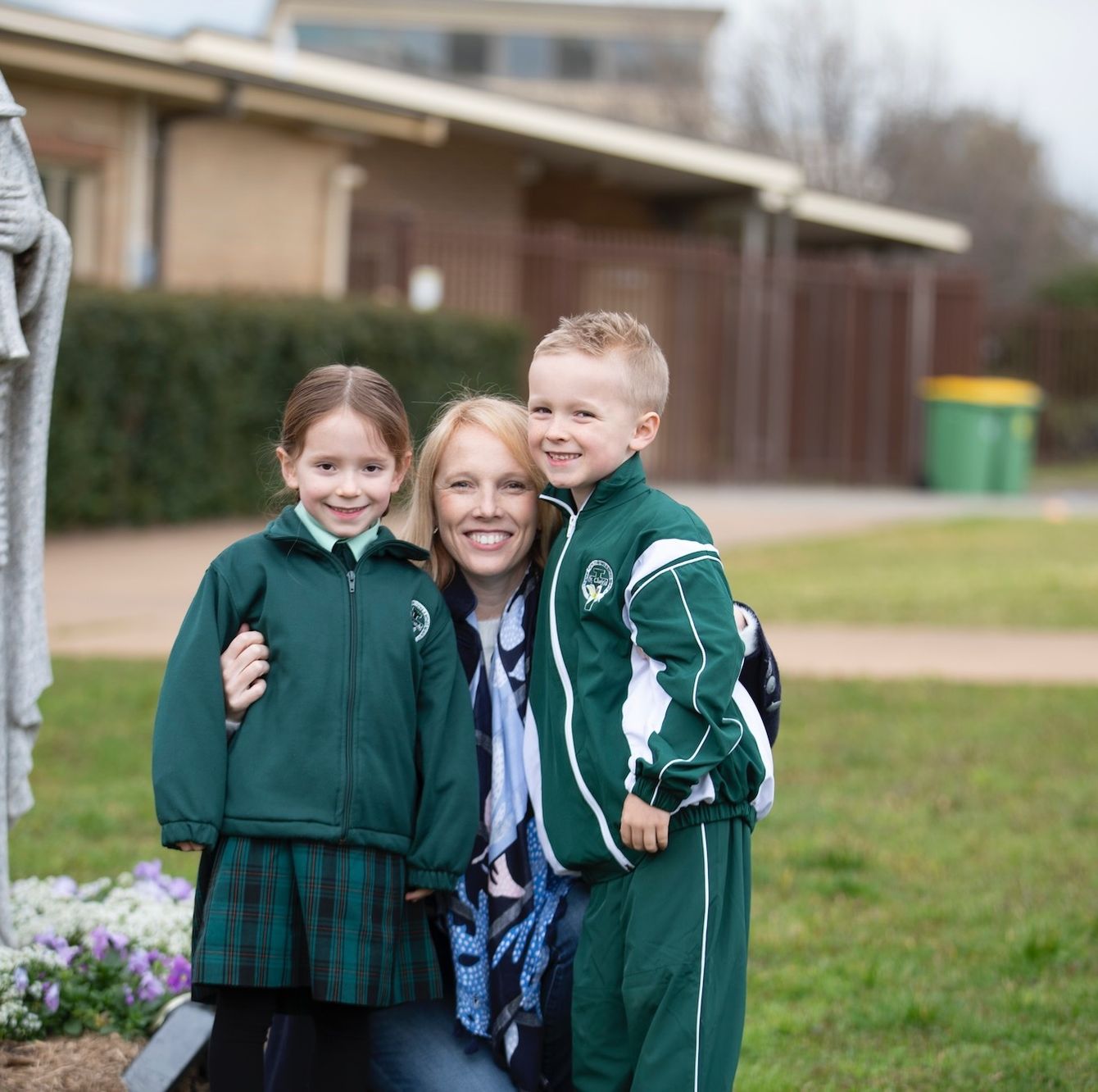 Primary school students standing next to religious statue with parent.