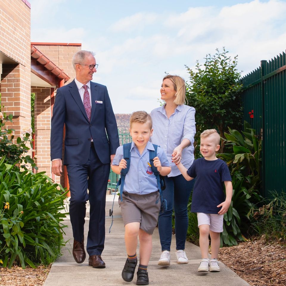 Primary school student walking with school principal and parent.