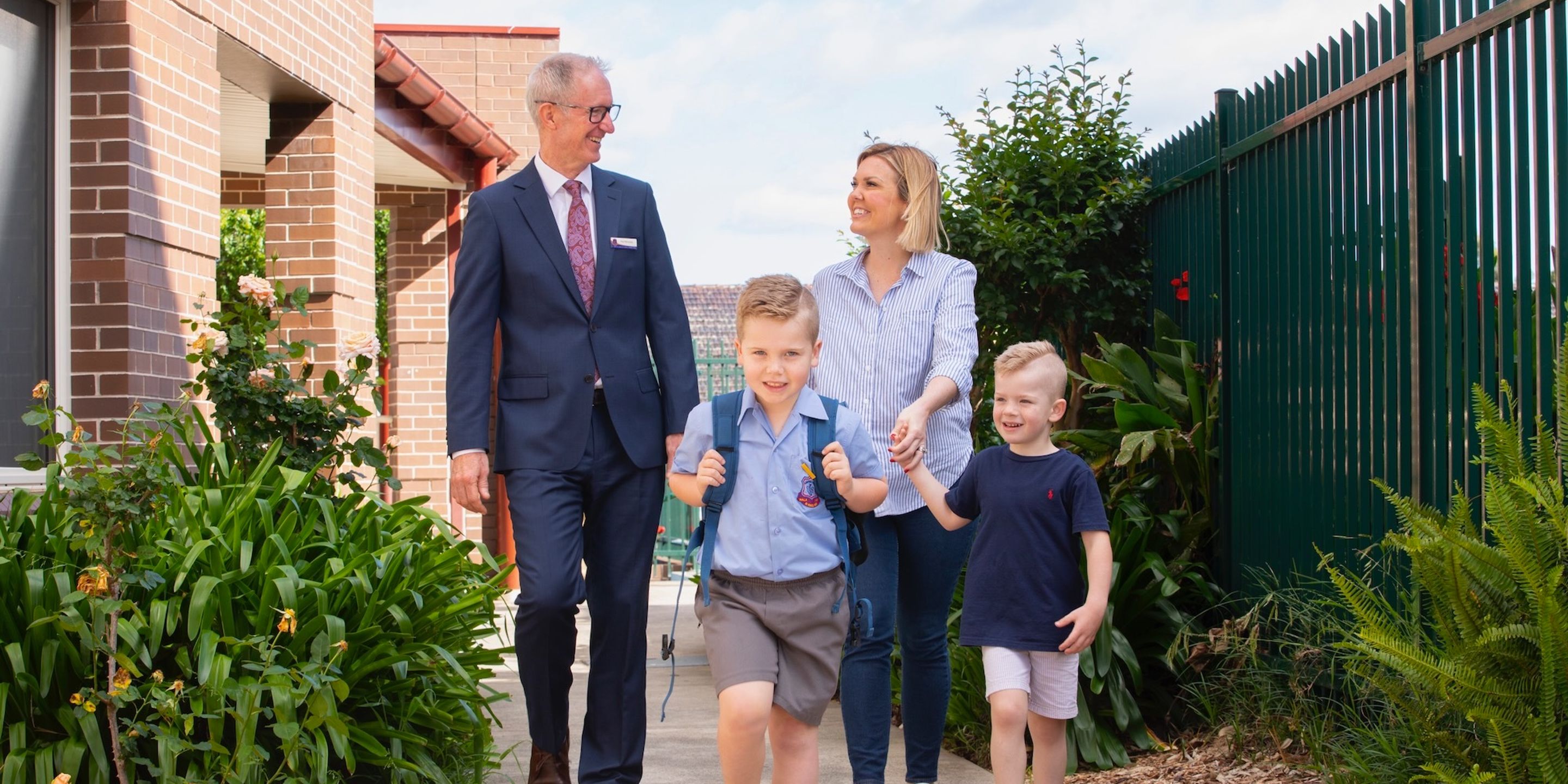 Primary school student walking with school principal and parent.