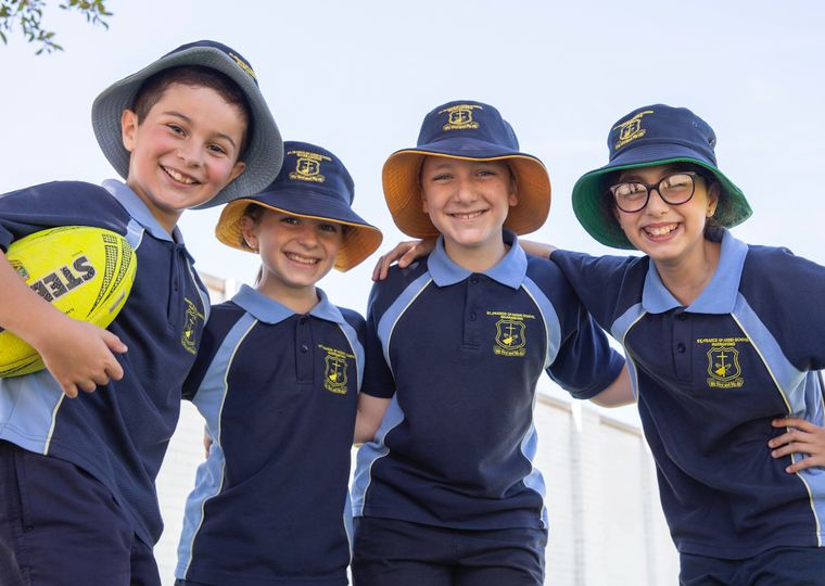 Primary school students with arms around each other looking down at camera.