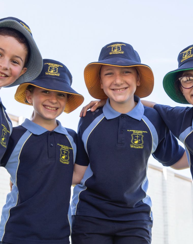 Primary school students with arms around each other looking down at camera.