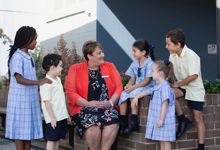 Primary school principal talking with five students.