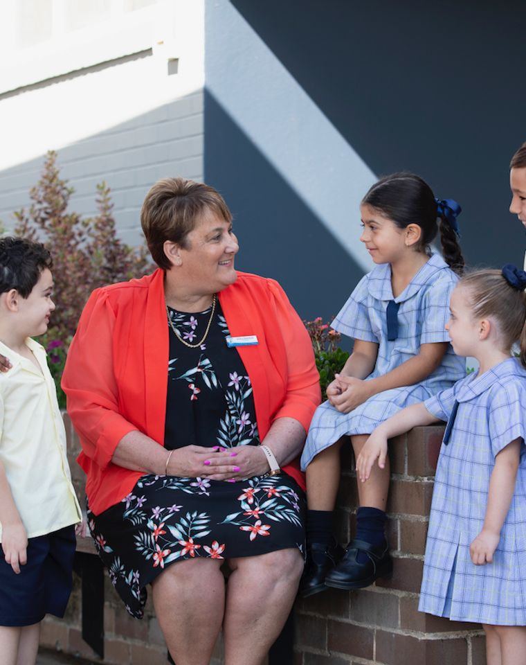 Primary school principal talking with five students.