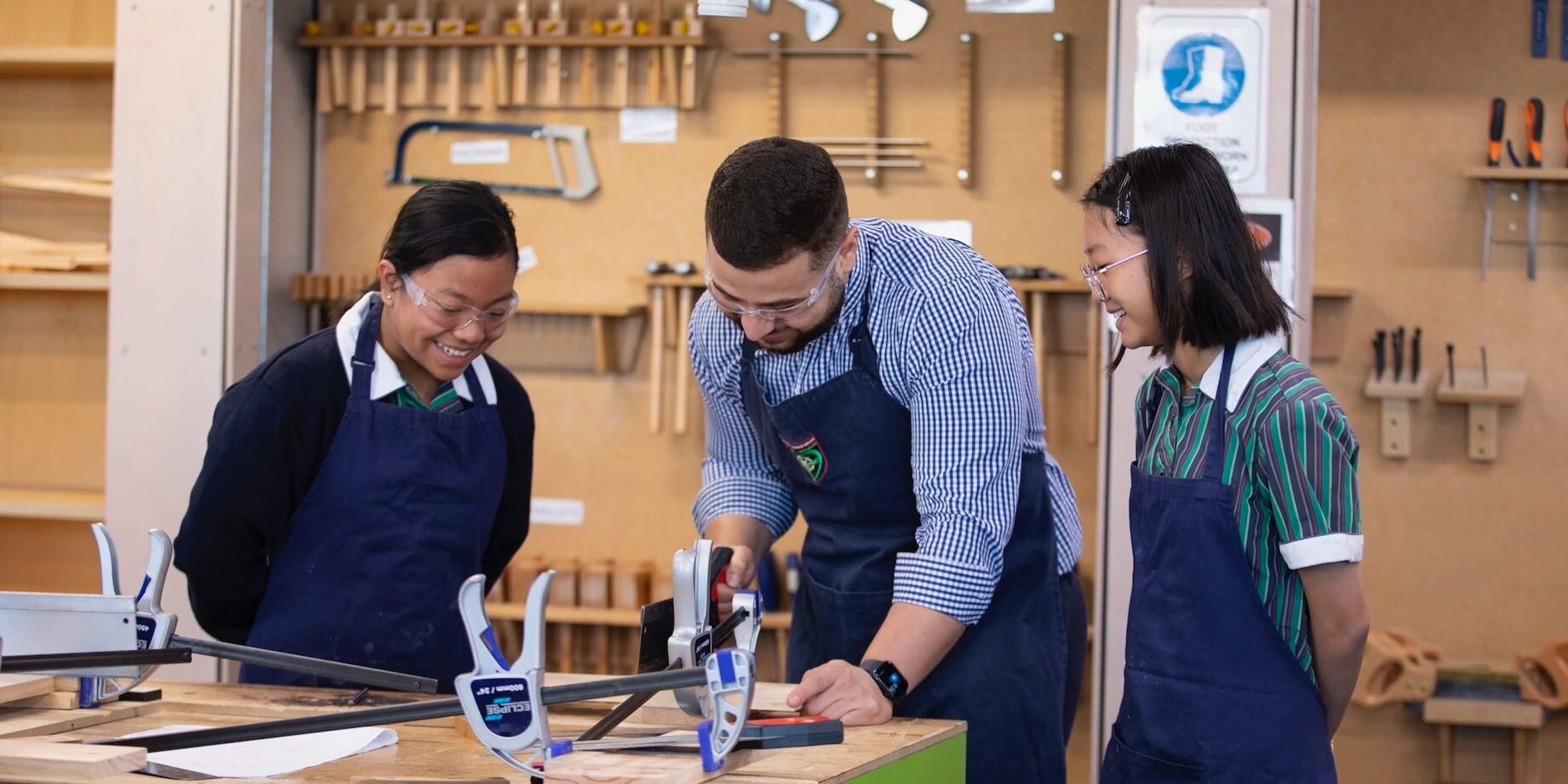 High school students watching teacher do woodwork.