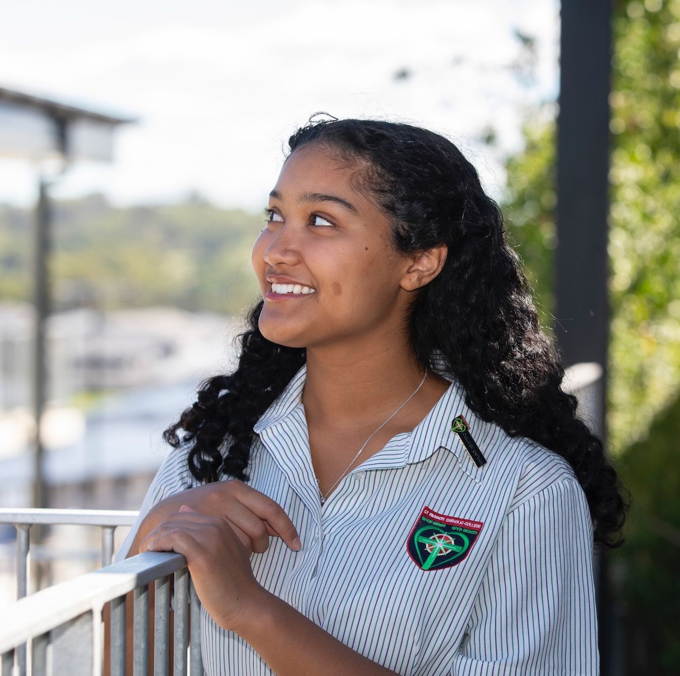 High school student looking out at sky over railing.