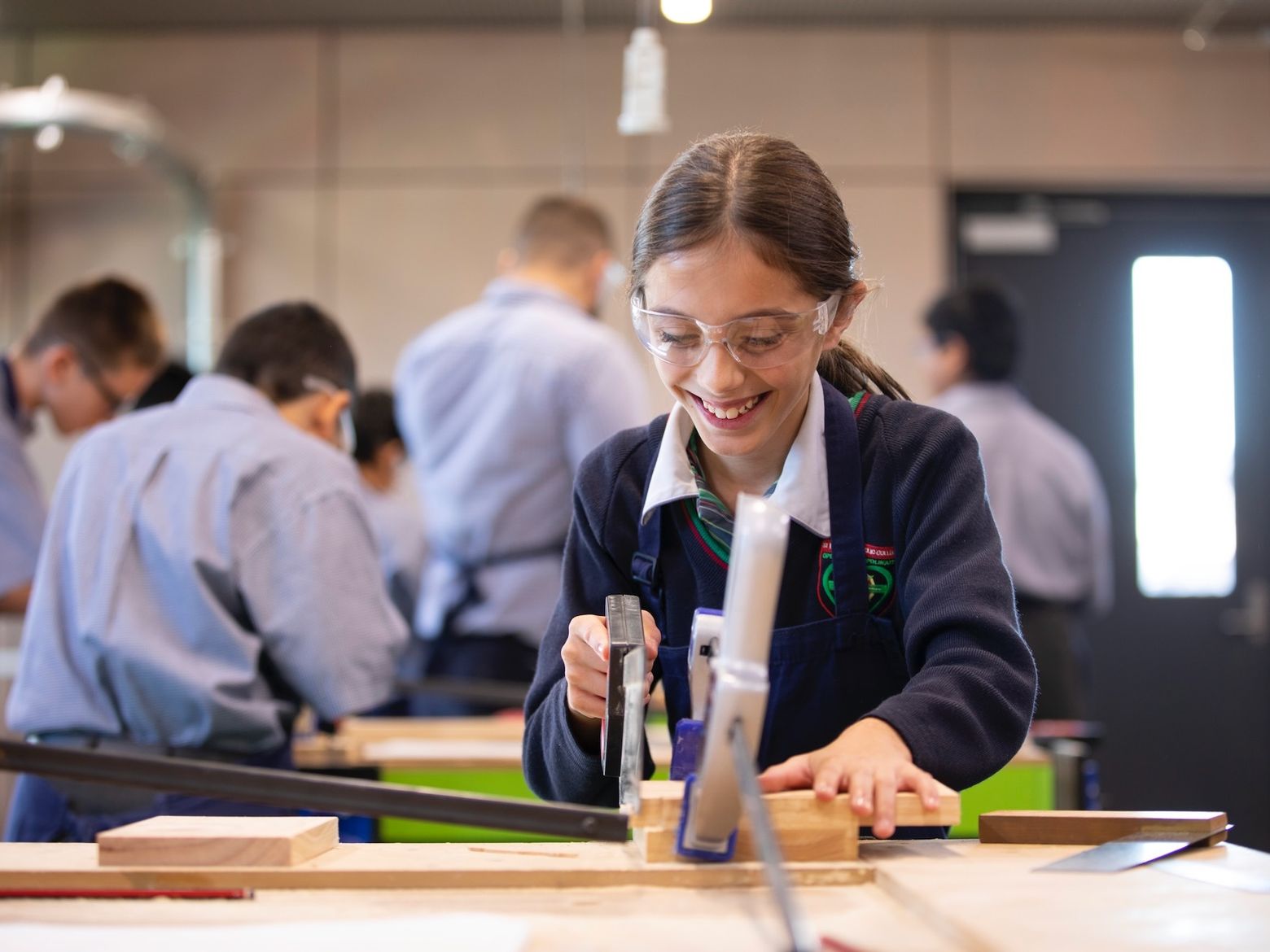 High school student doing woodwork and smiling.