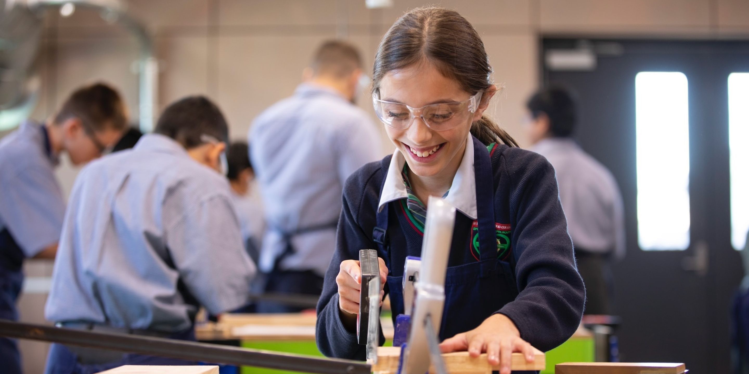 High school student doing woodwork and smiling.