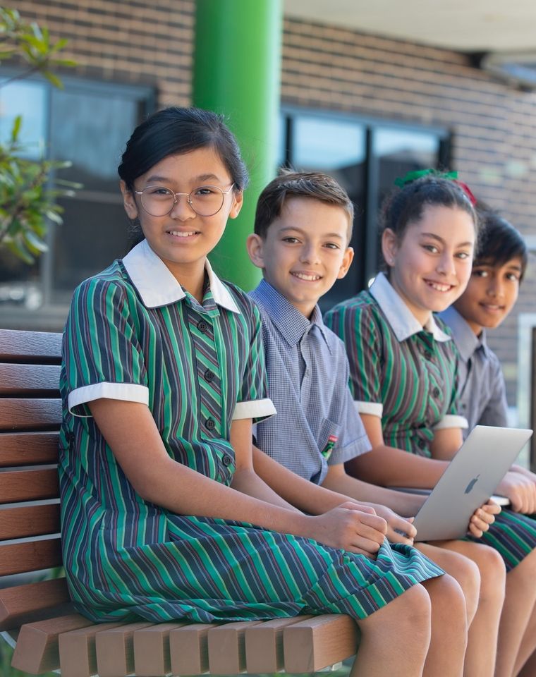 High school students sitting on bench and smiling at camera.