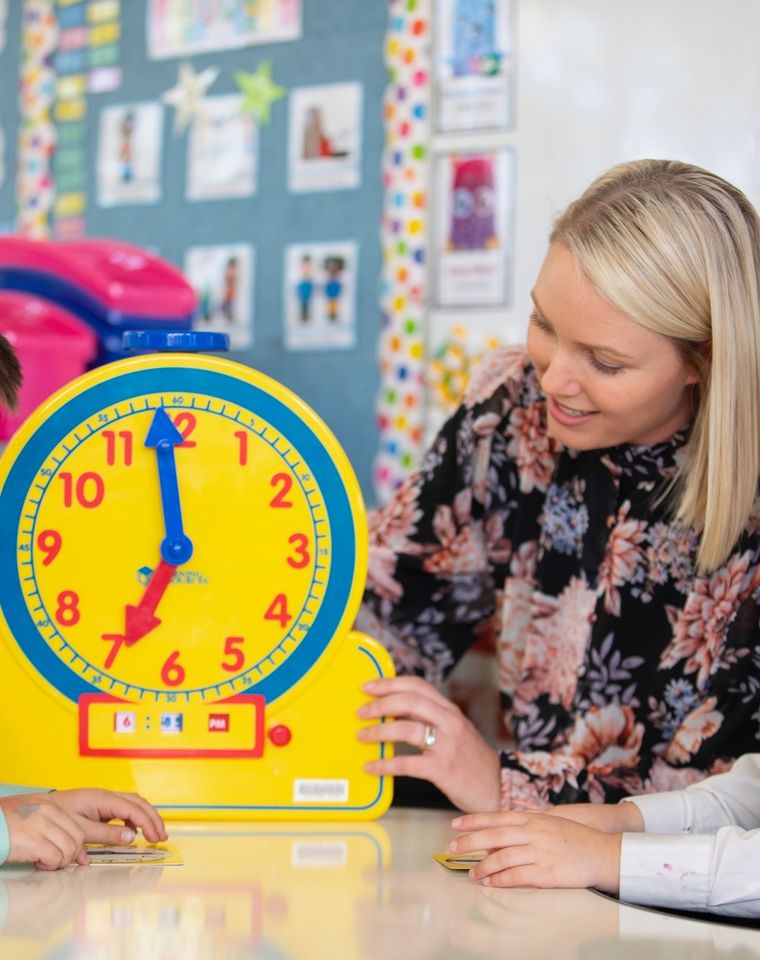 Two primary school students doing maths activity with teacher.