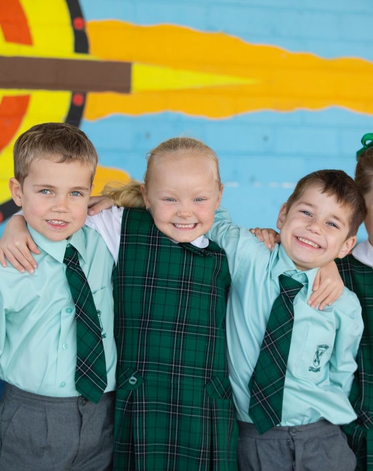 Group of students standing together with arms around each other.