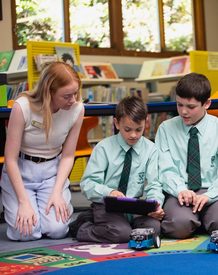 Group of primary school students learning about technology with teacher.