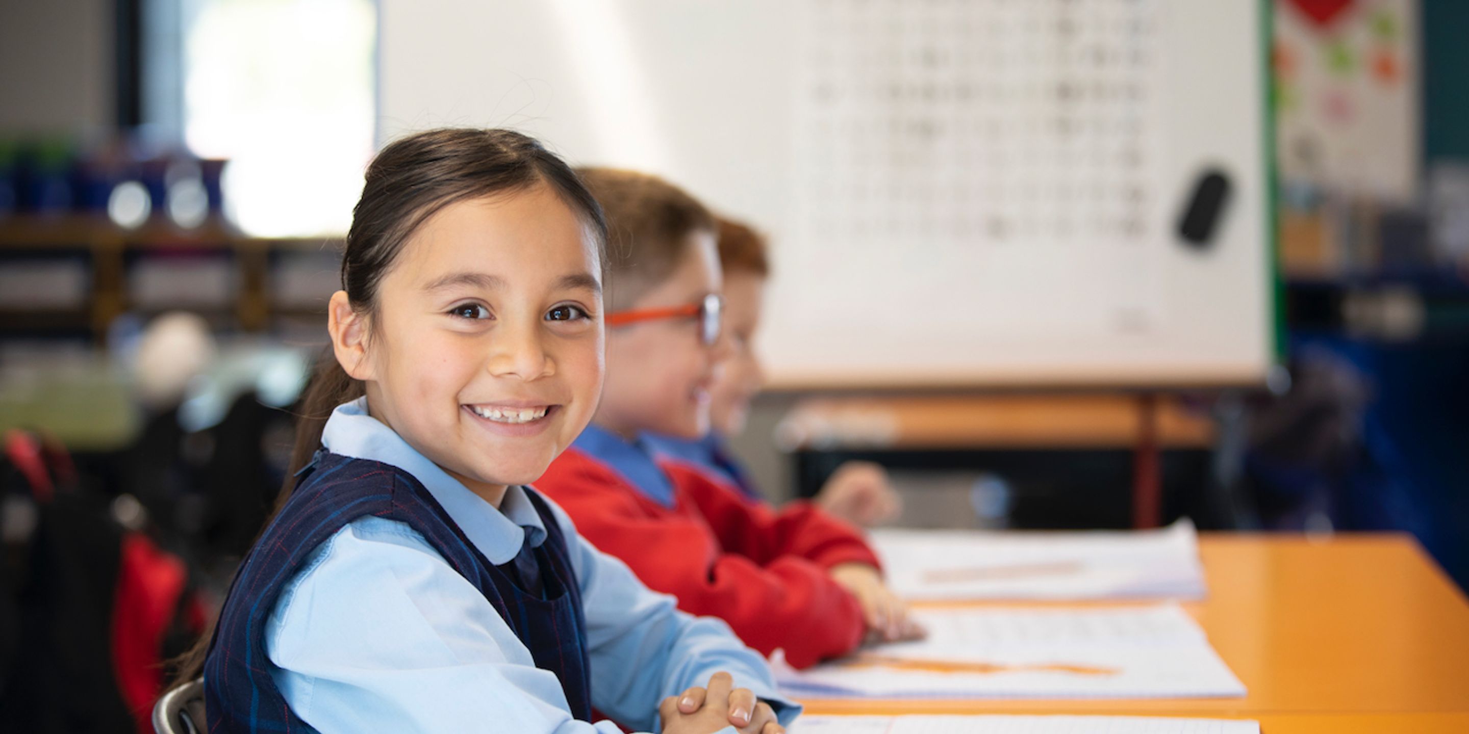 Primary school student smiling at desk.