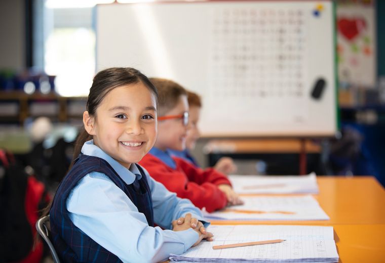 Primary school student smiling at desk.