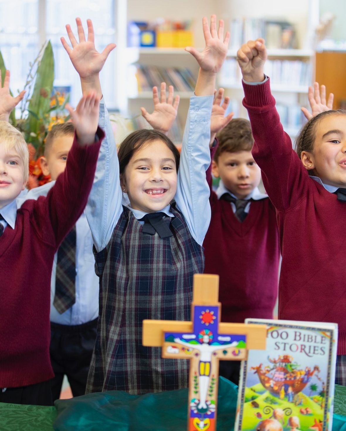 Primary school students smiling with arms up in religion class.