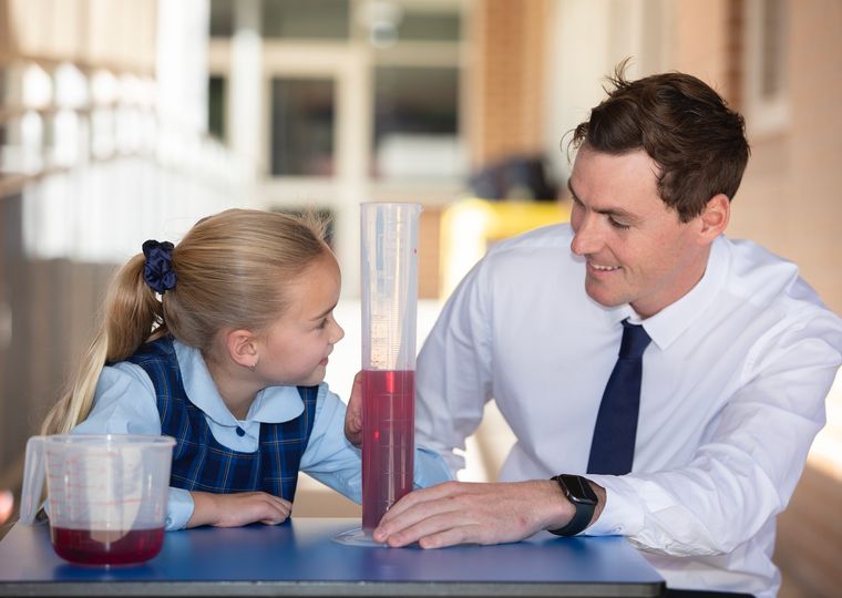 Primary school student doing science experiment with teacher.