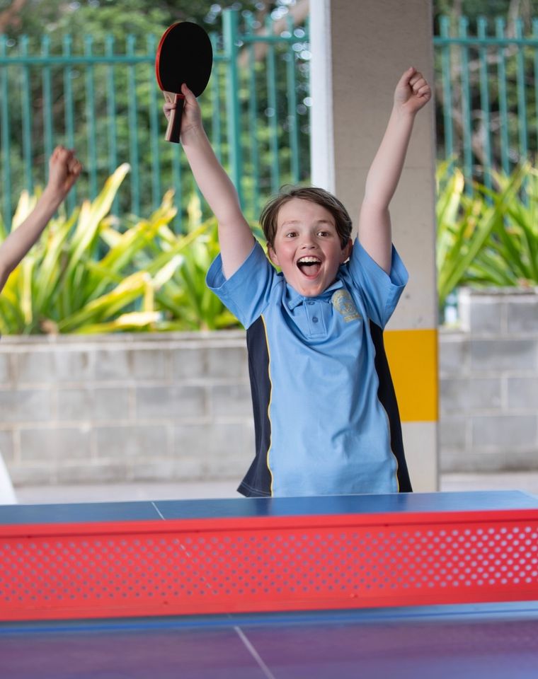 Primary school students cheering during a game of table tennis.