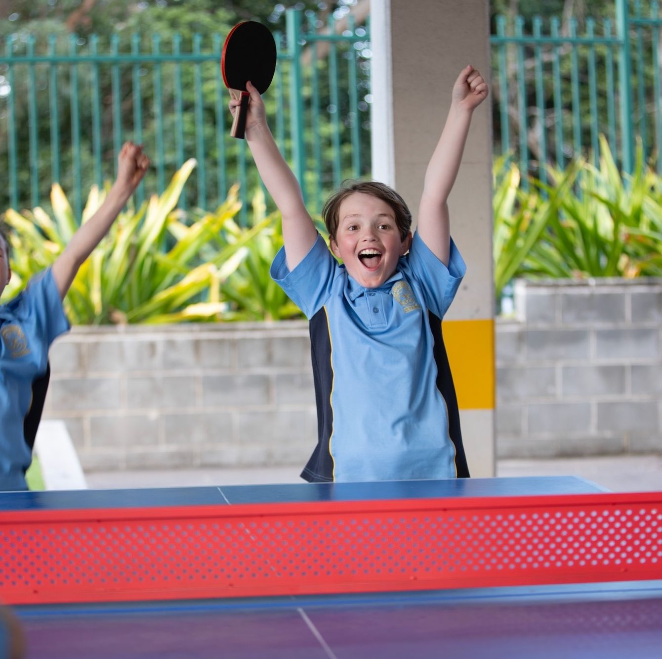 Primary school students cheering during a game of table tennis.