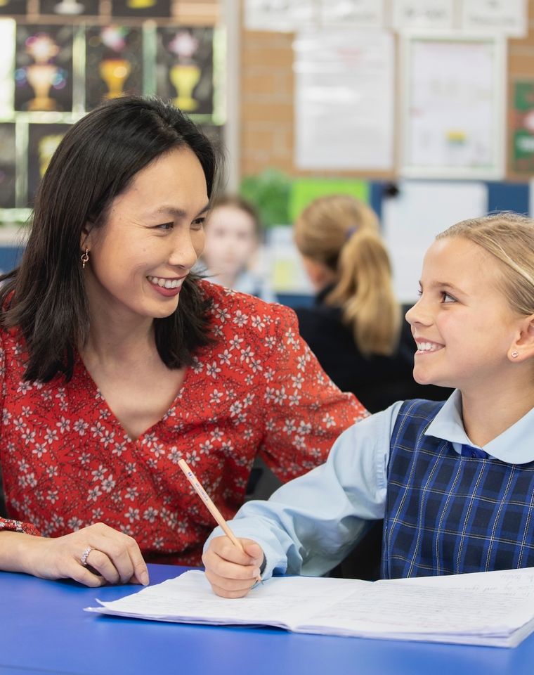 Primary school student doing schoolwork with teacher.