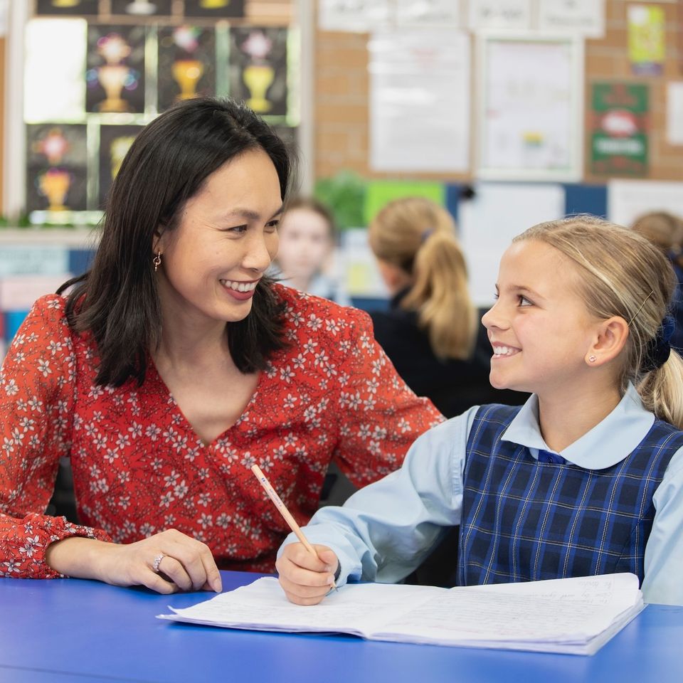 Primary school student doing schoolwork with teacher.