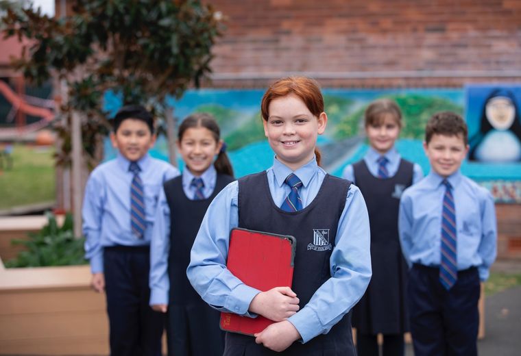 Group of primary school students standing and smiling at camera.