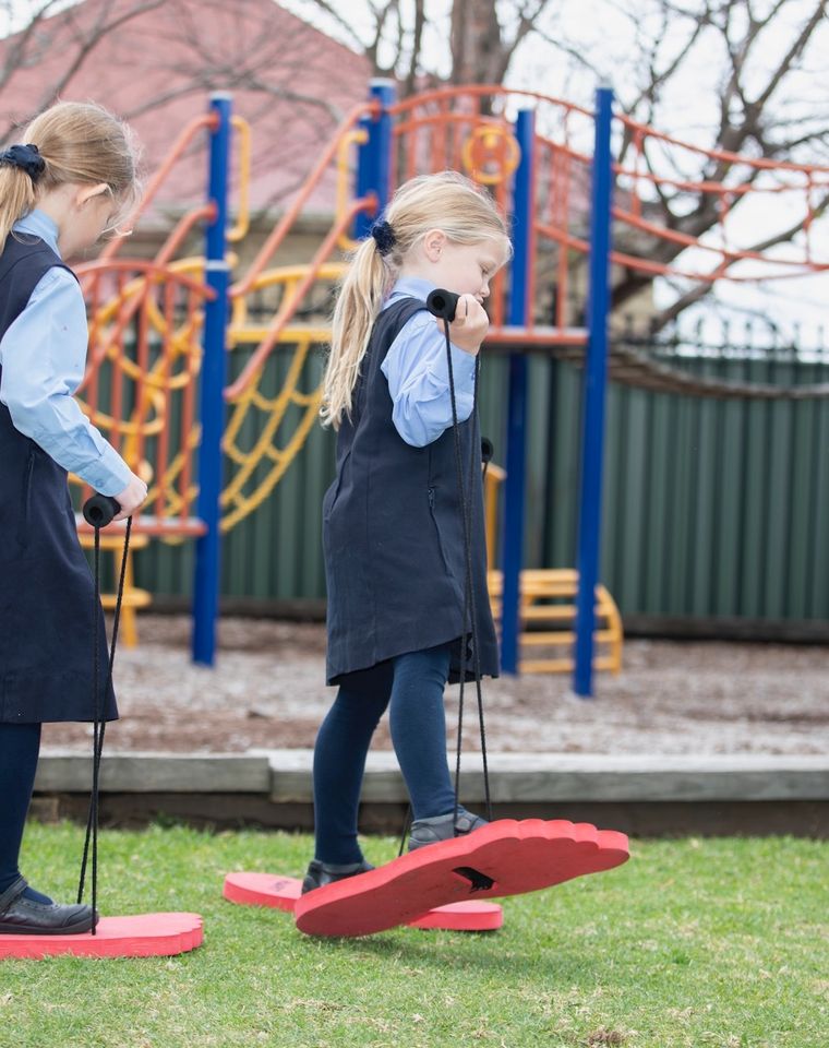 Two primary school students doing activity on grass playground.