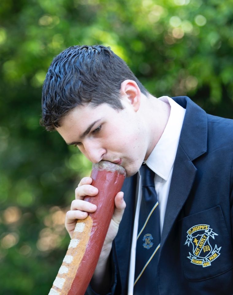 High school student playing didgeridoo.