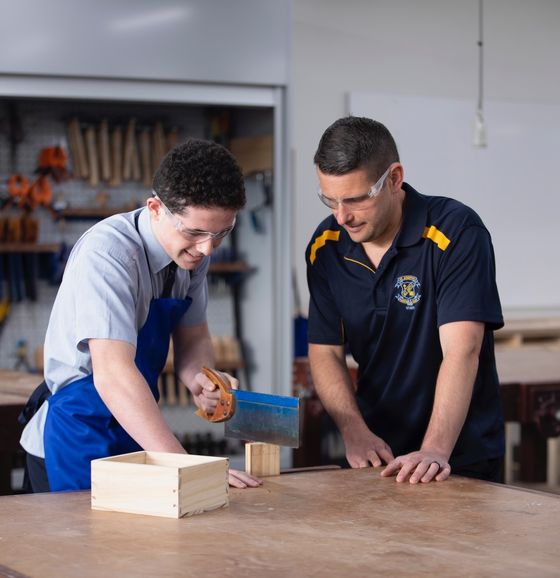 High school student doing woodwork with teacher.