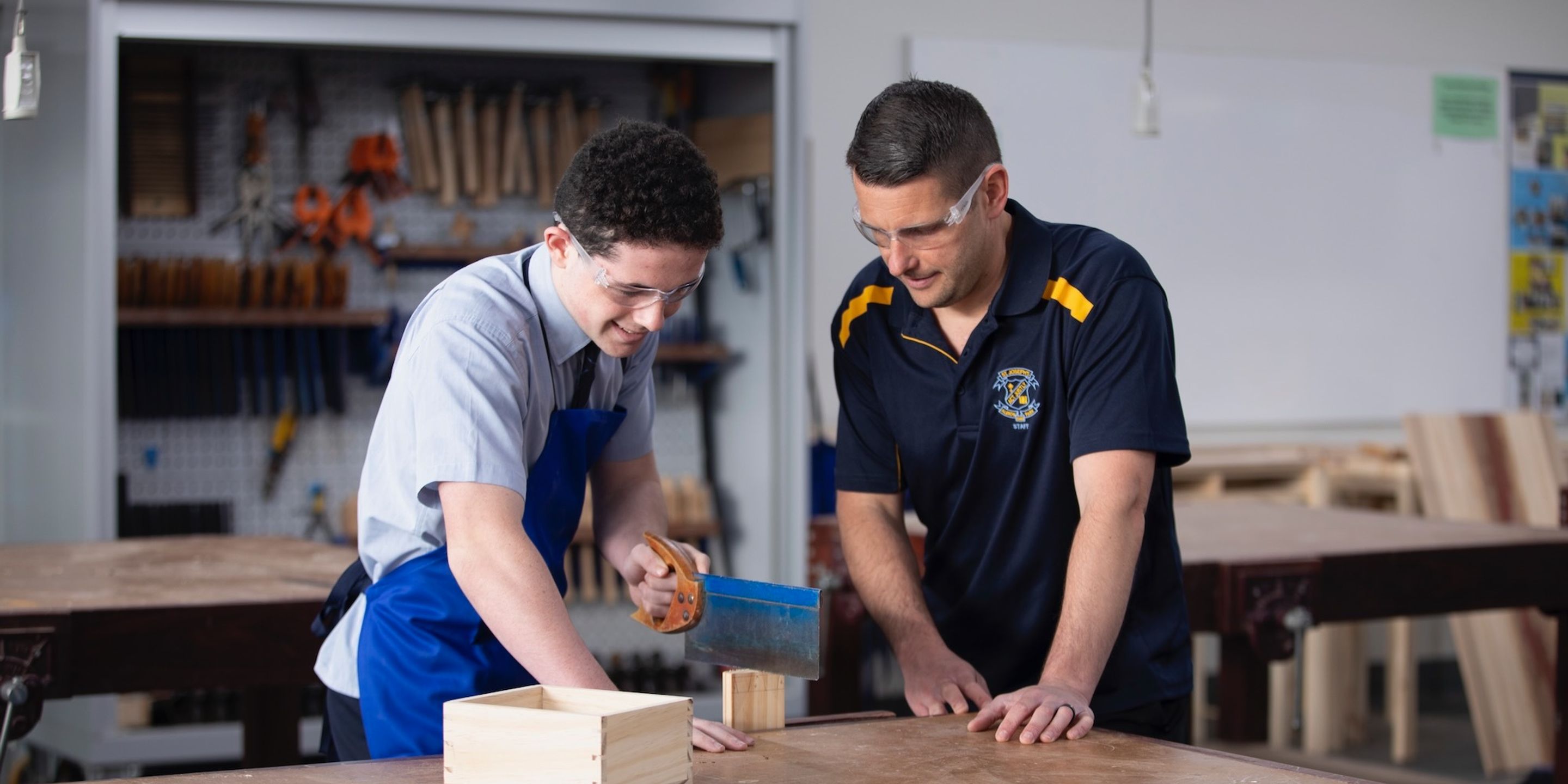 High school student doing woodwork with teacher.