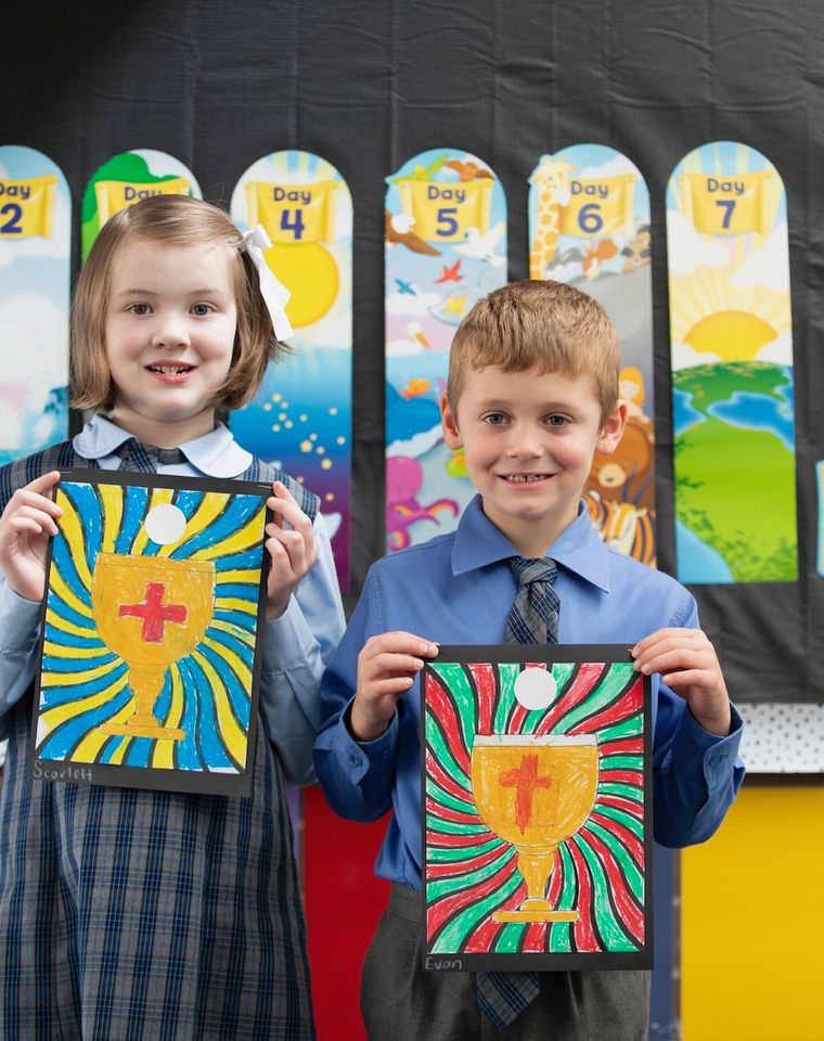 Primary school students holding up religious artworks.