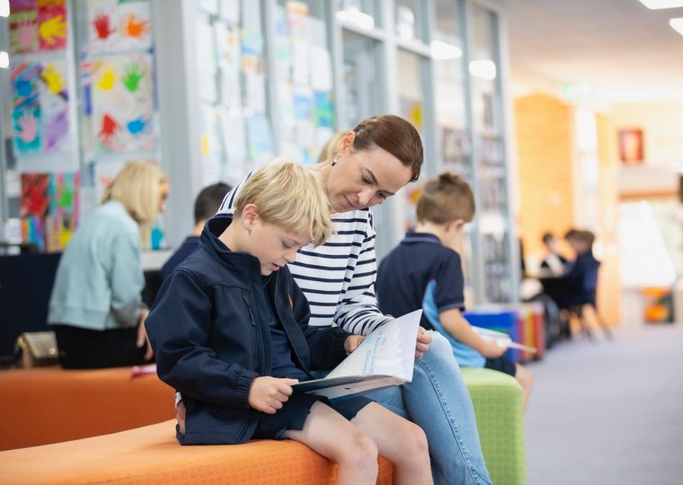 Primary school student reading a book with parent.