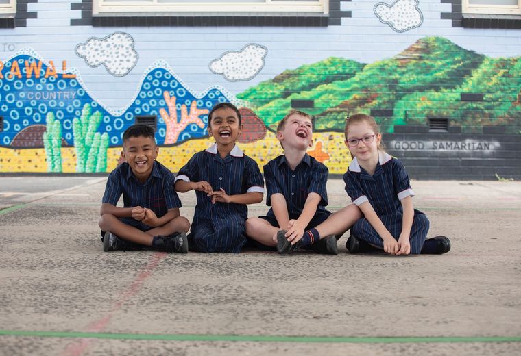 Primary school students laughing on concrete.