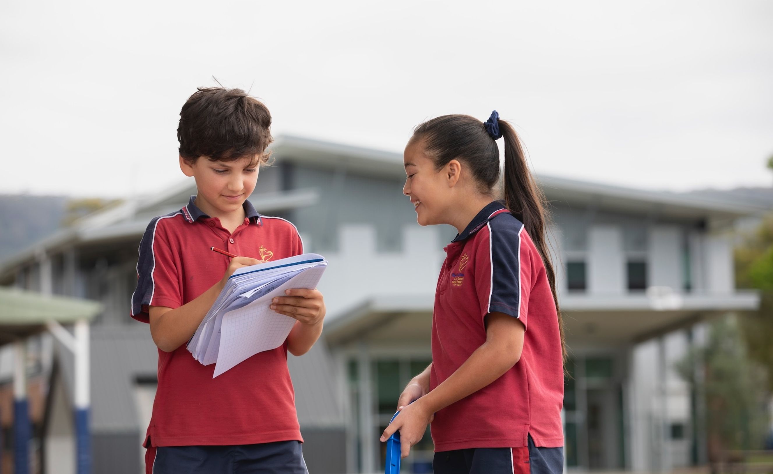 Primary school students outdoors with notebook.