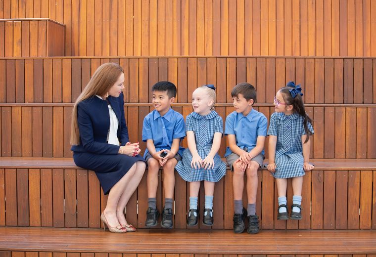 Primary school students sitting with school principal.