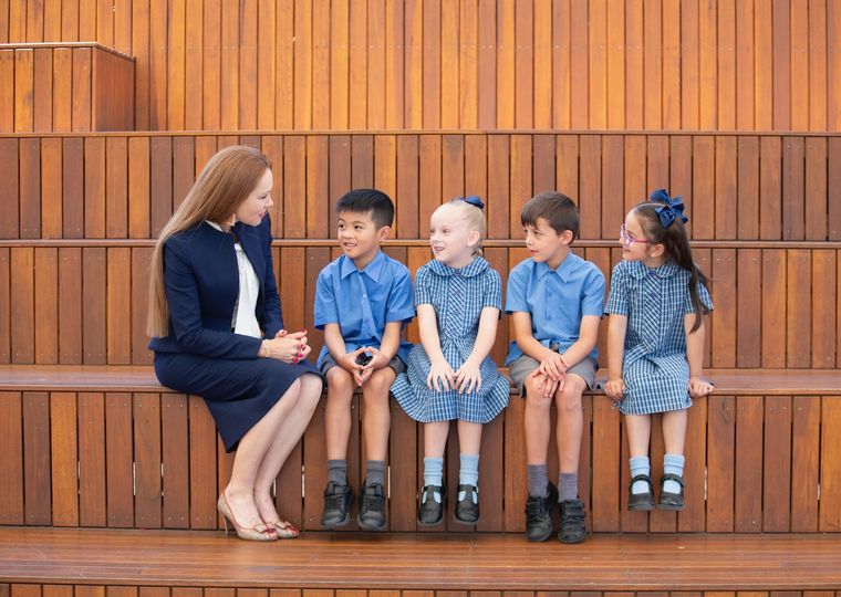 Primary school students sitting with school principal.