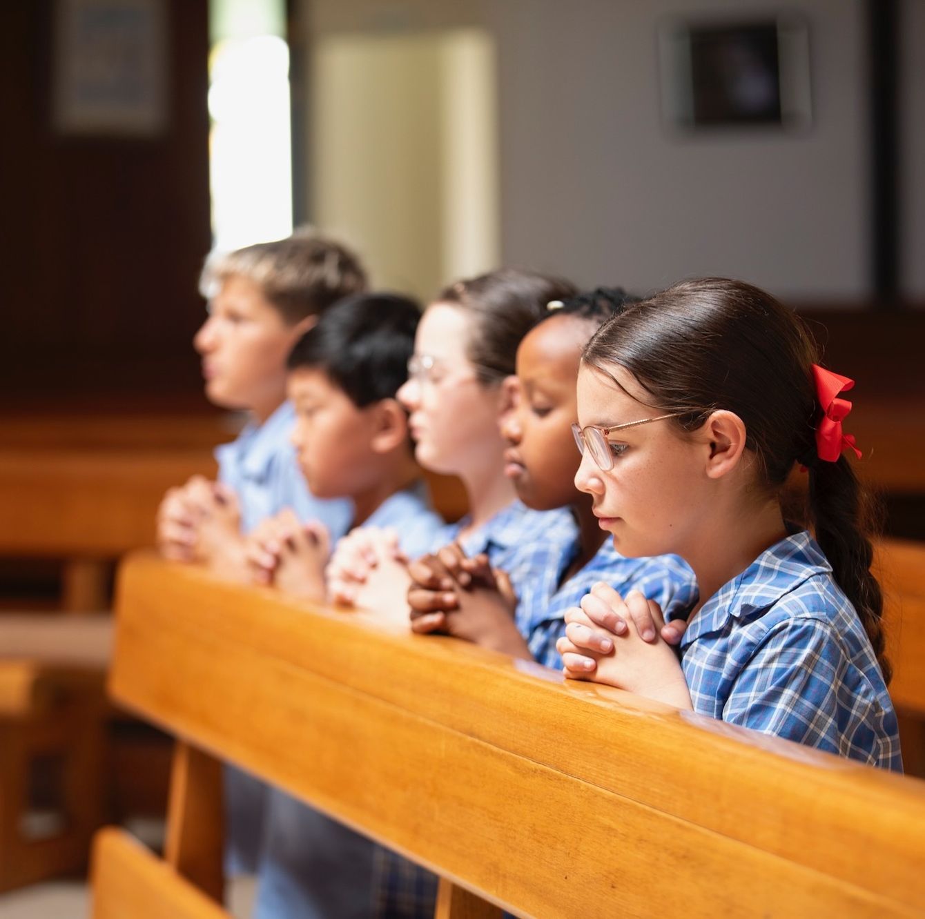 Primary school students praying in church.