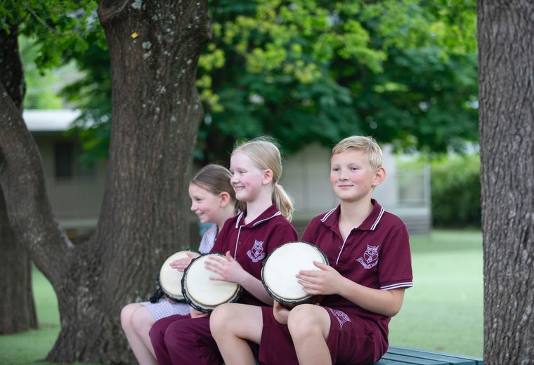 Primary school students playing drums outdoors.