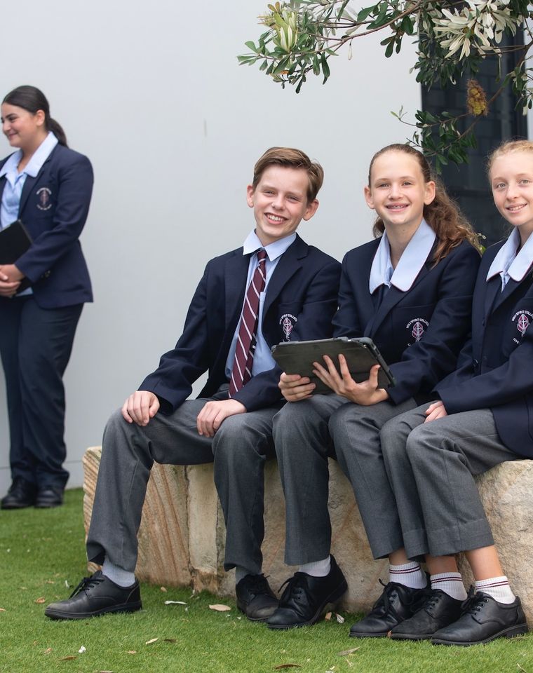 High school students sitting on bench with laptop.