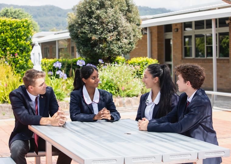 High school students talking at table outdoors.