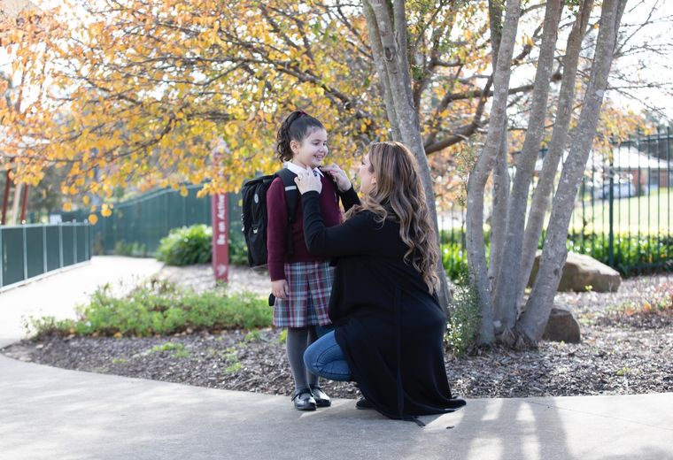 Primary school student with parent outdoors.