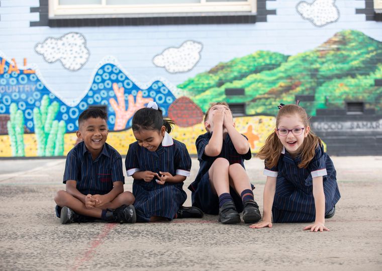 Four children laughing on the concrete